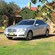 A sedan with a sign on the roof that says TAXI is parked in the grass in front of a building